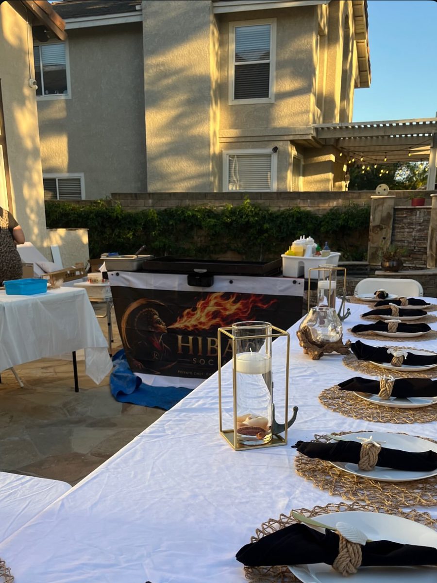 Place settings and candles on a long table next to the hibachi grill