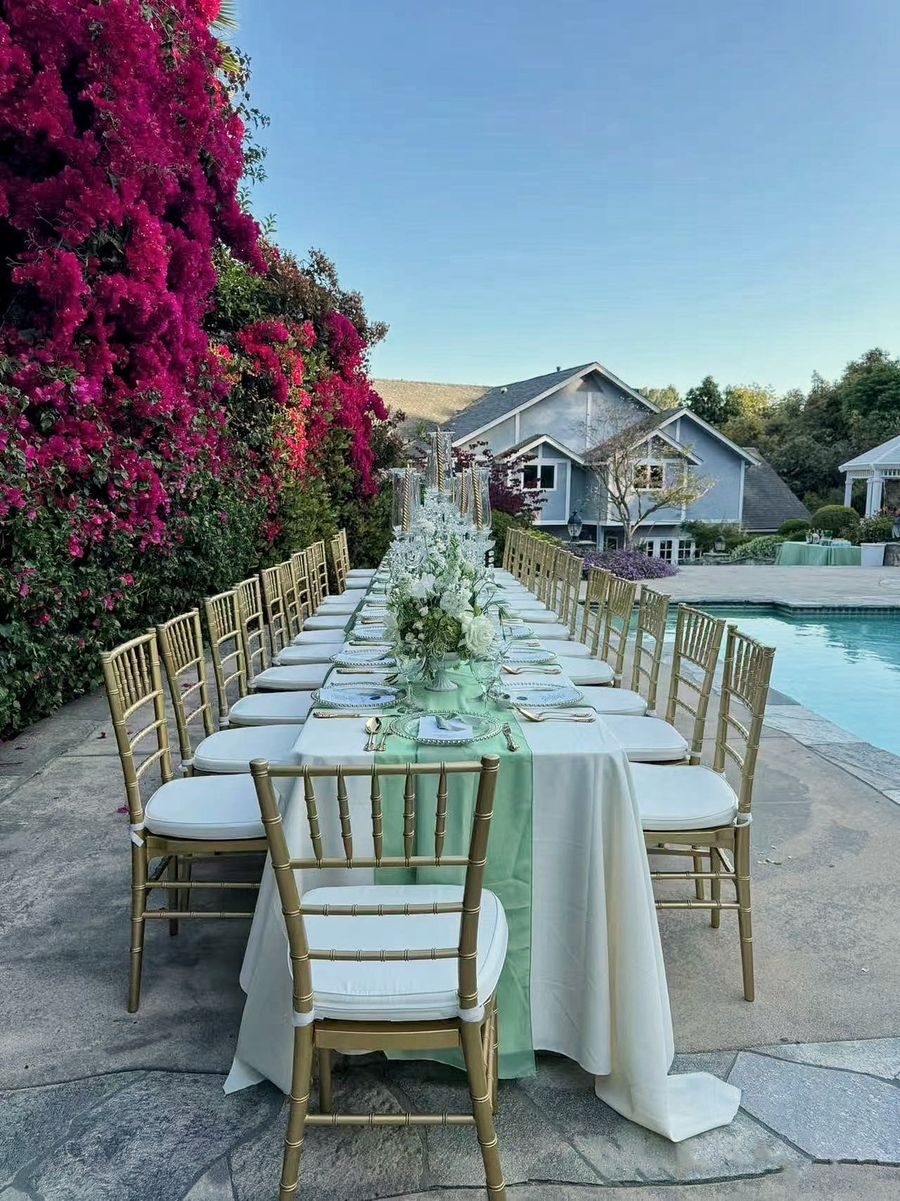 Long table set beside a pool at golden hour before a private dinner